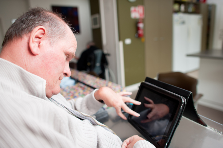 Senior male with Cerebral Palsy using tablet